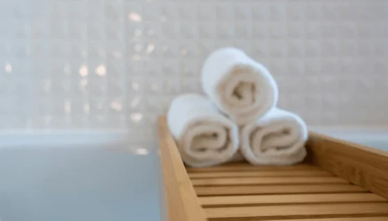 a stack of rolled white towels on a wooden tray